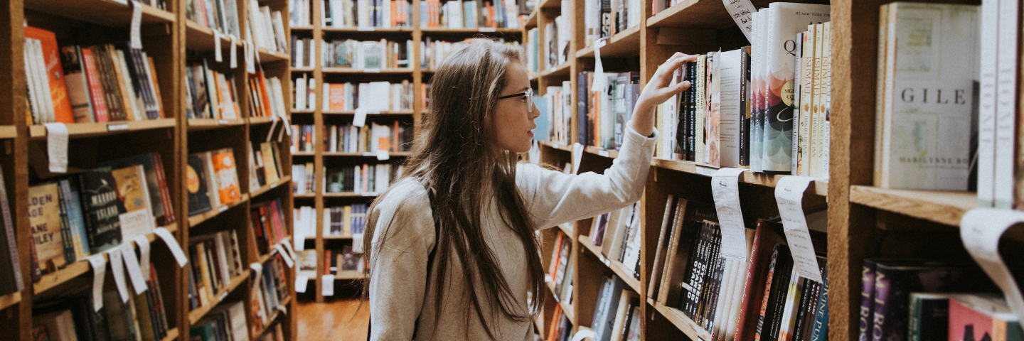 Una estudiante en la búsqueda de un libro en una biblioteca